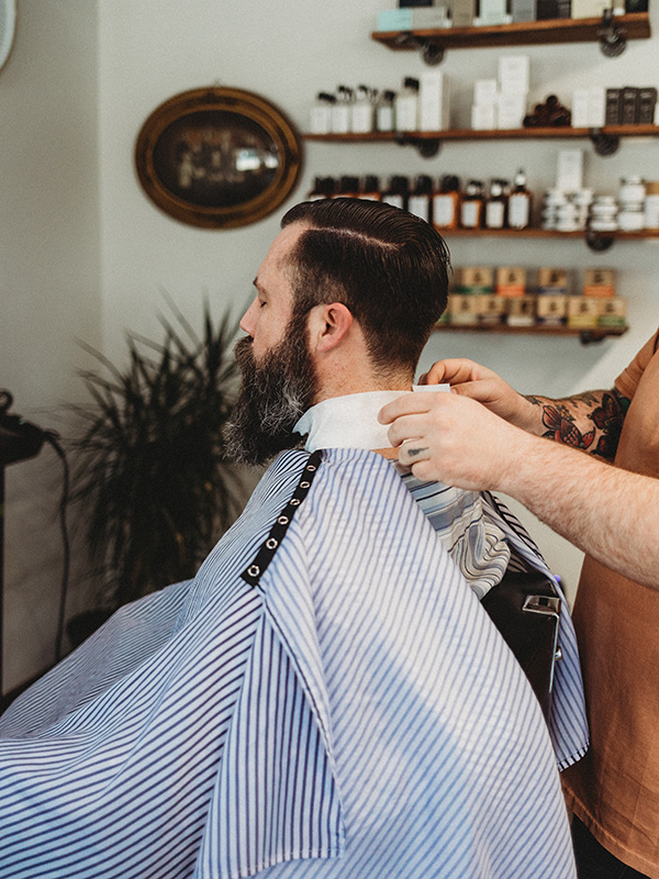 Barber putting apron on client in barber chair