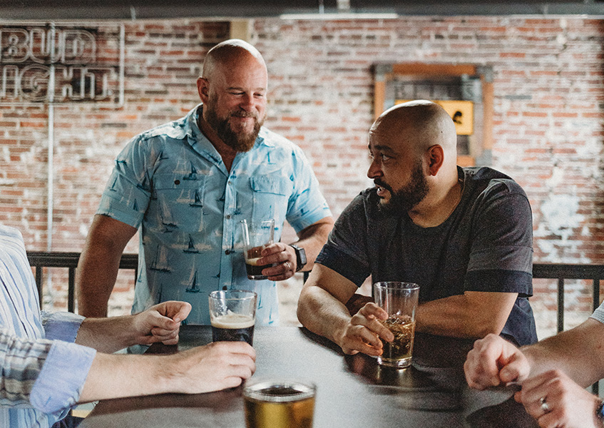 Friends drinking beer together at bar after haircuts