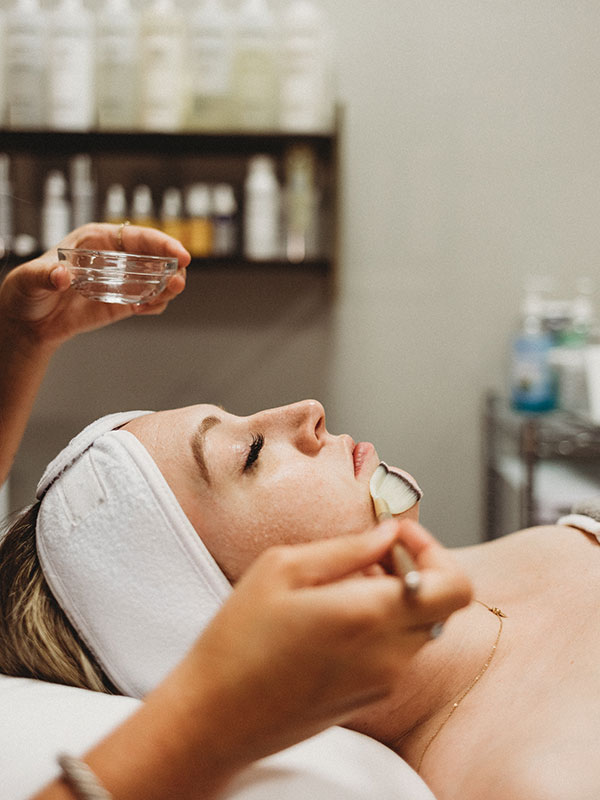 Esthetician brushing patient with product