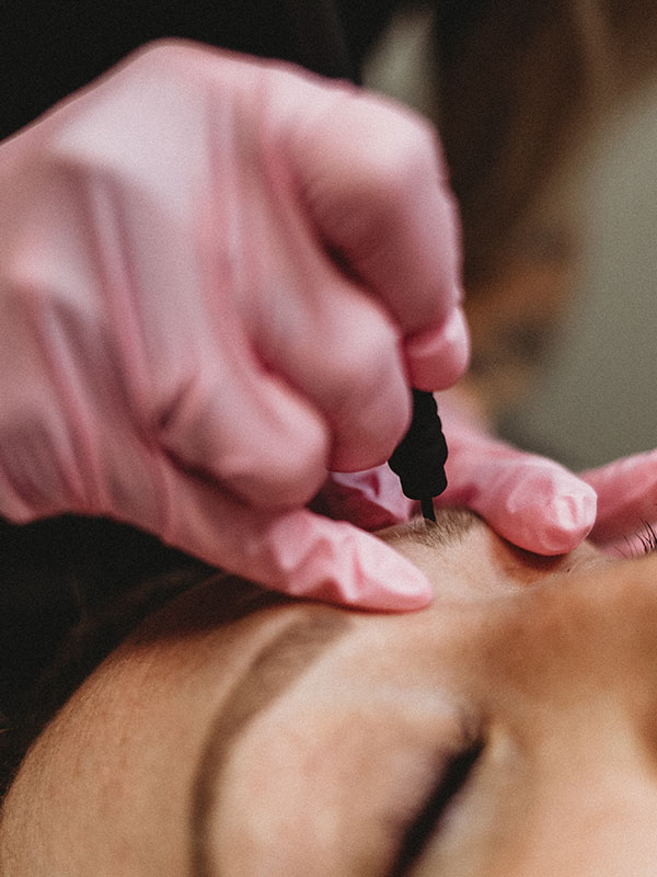 Close up of microblading with pink glove